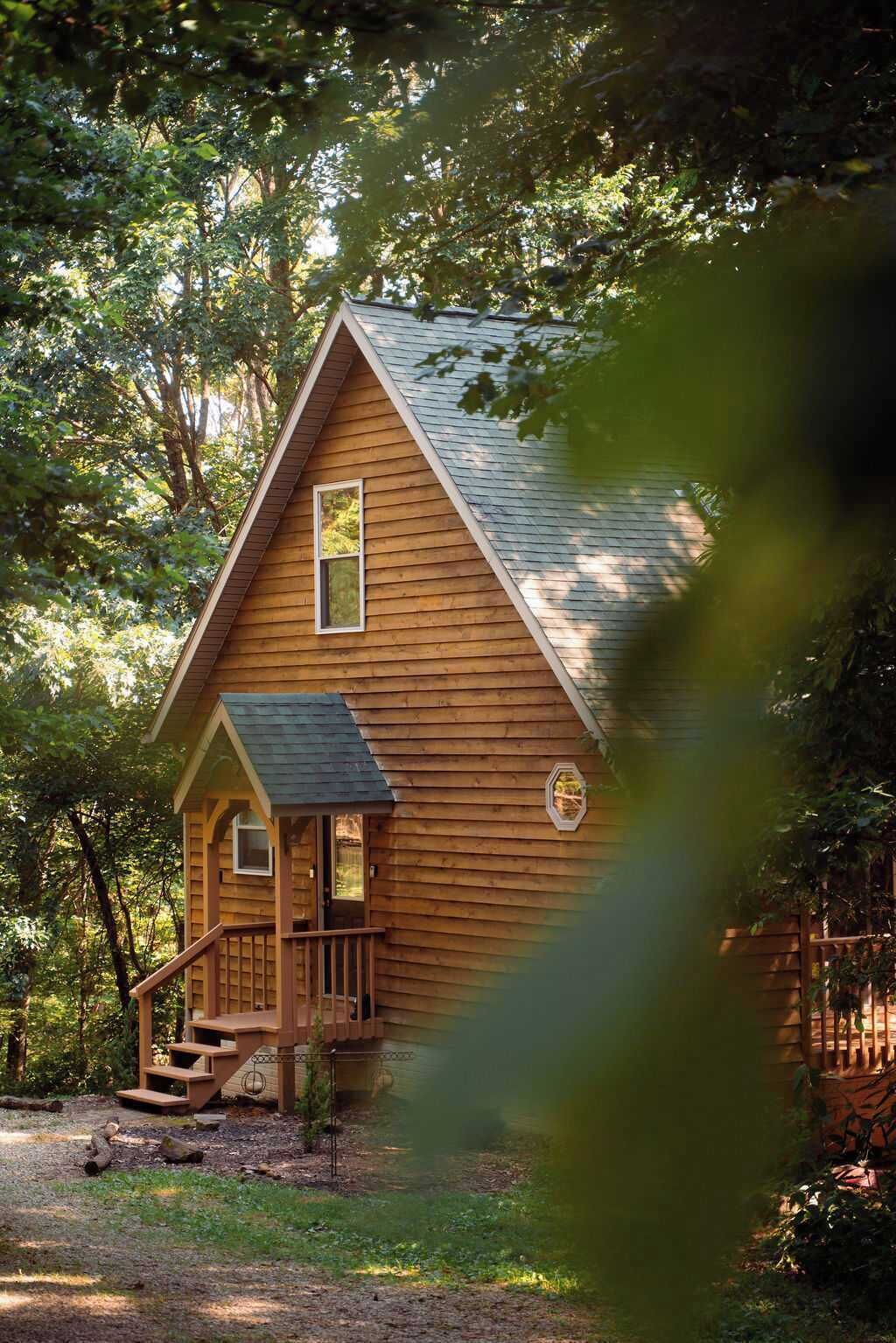 Une cabane en bois avec un toit à forte pente, un porche à l’avant et un petit escalier menant à l’entrée.