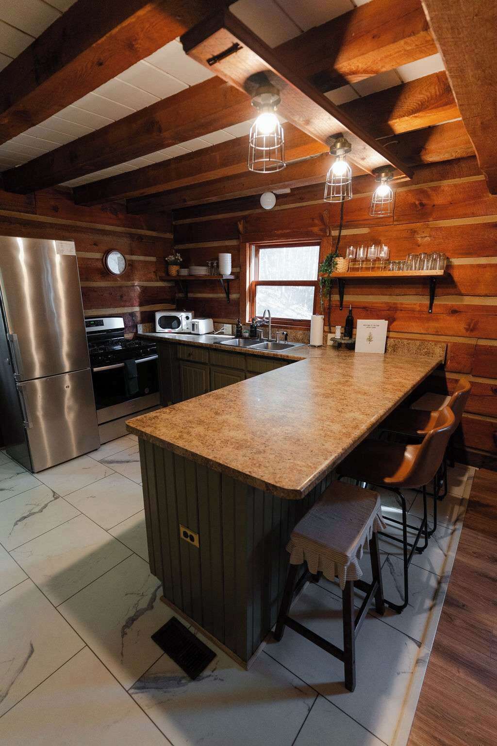 Una cocina con isla central, electrodomésticos de acero inoxidable y vigas de madera.