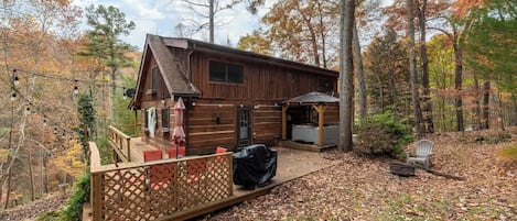 A cabin with a deck, outdoor seating, and a covered area.