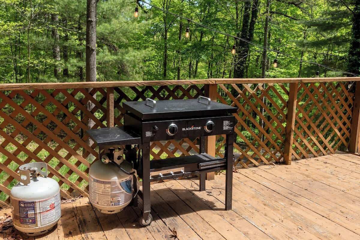 Un barbecue portable sur une terrasse en bois, avec une clôture en treillis en arrière-plan.