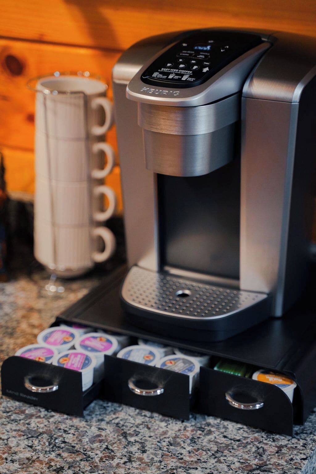 Une machine à café Keurig avec un compartiment à dosettes, posée sur un comptoir en granit.