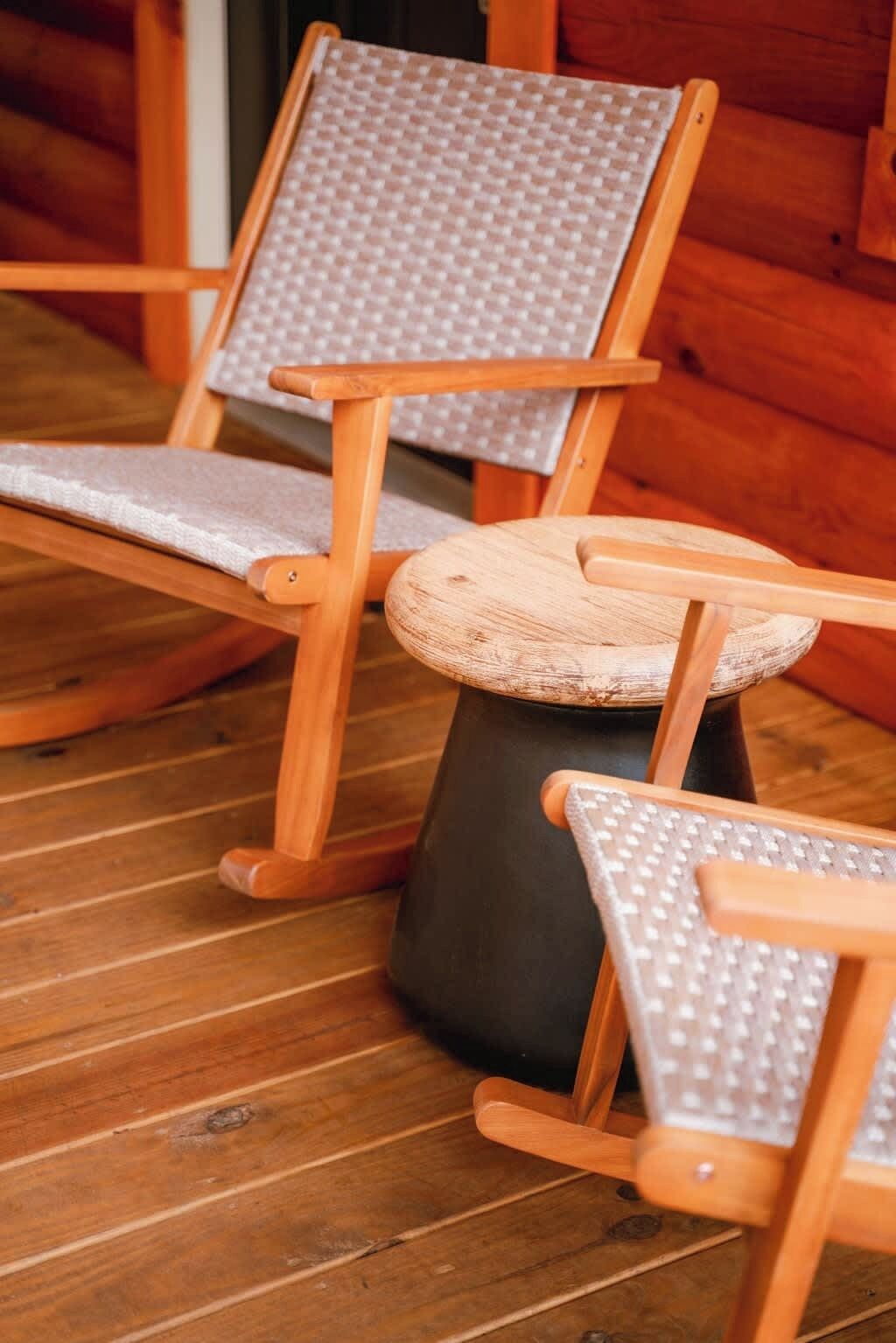 Zwei hölzerne Schaukelstühle mit gepolsterten Sitzen und Lehnen, auf einem Holzboden platziert.