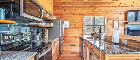 A modern kitchen with wooden walls and a central island, equipped with stainless steel appliances and granite countertops.