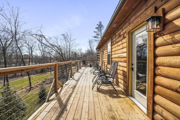 A wooden cabin with a deck, outdoor seating, and a view of the surrounding forest. - Modern Luxury I Hot Tub I Hiking (McArthur)