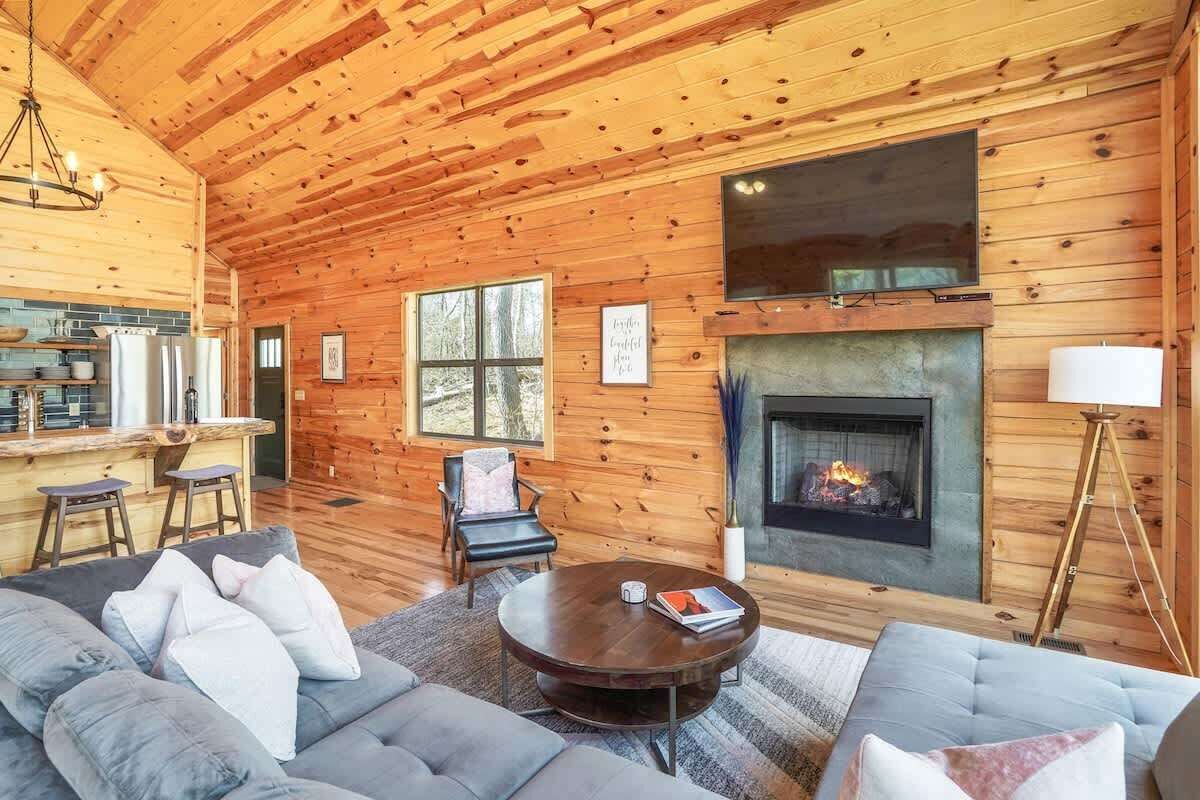 Interior acogedor de una cabaña con detalles de madera, una chimenea, un sofá y un comedor.