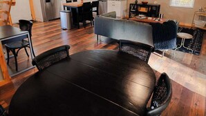 A spacious kitchen with white cabinets, a stainless steel refrigerator, and a dining area with a round table and chairs. - The Treetop Retreat Family Getaway in Scenic Hocking Hills (Logan)