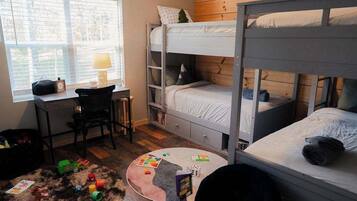 A room with bunk beds, a desk, a chair, and a ceiling fan.