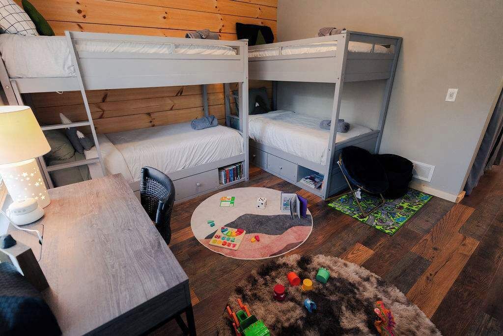 A bunk bed room with a desk, chair, and a small rug.