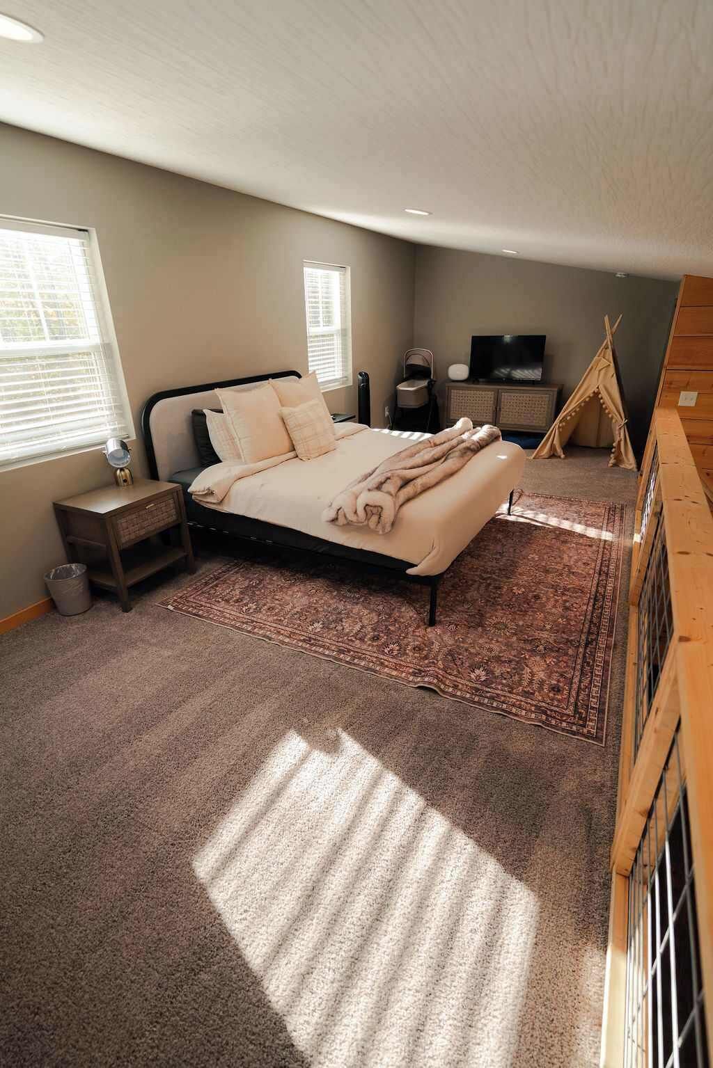 A bedroom with a bed, a TV, a wooden bench, and a tent.