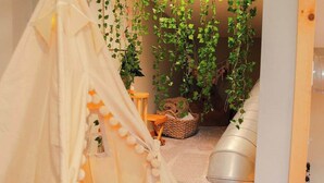 A cozy room with a white teepee, a small table with a basket, and hanging plants creating a green canopy. - The Treetop Retreat Family Getaway in Scenic Hocking Hills (Logan)