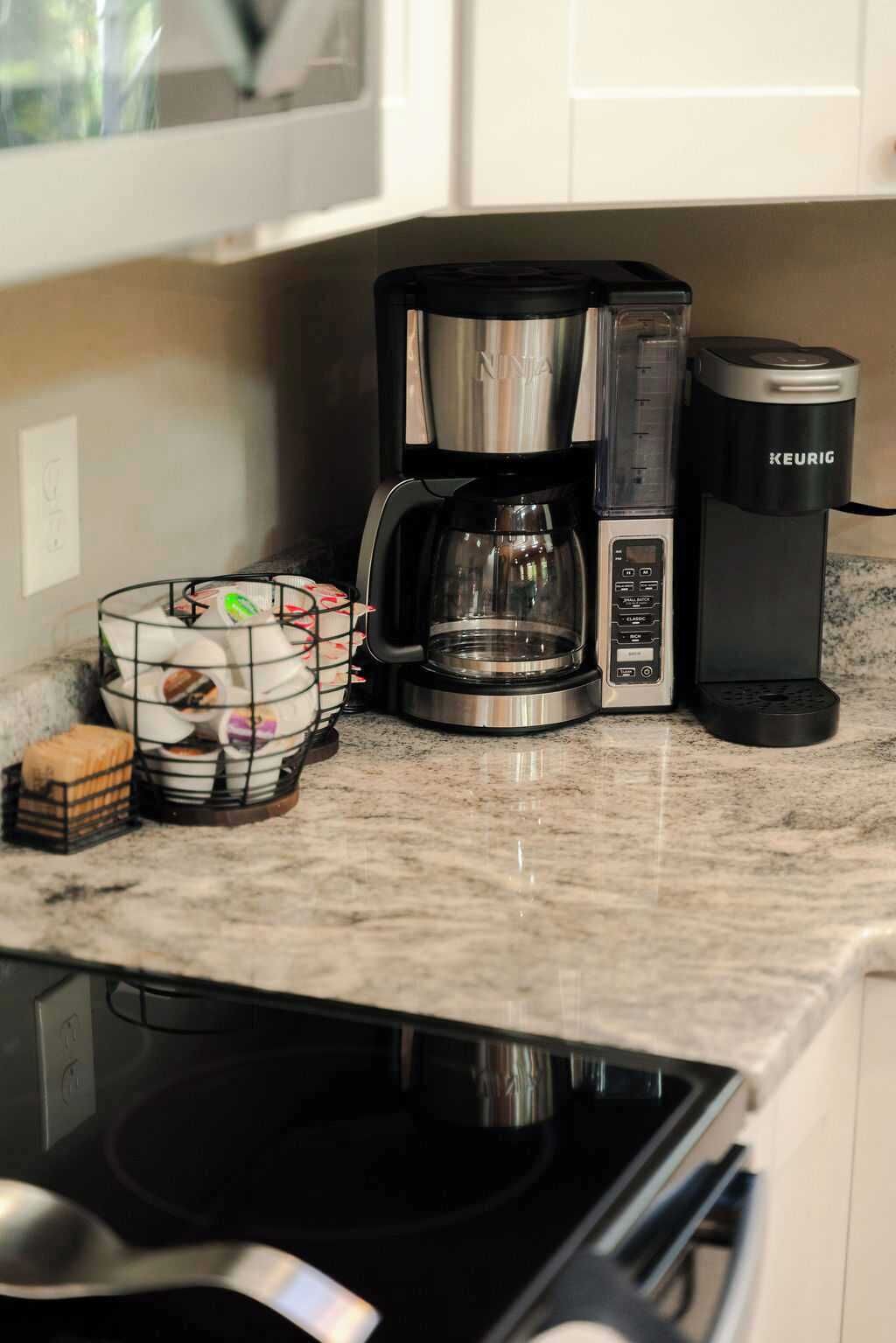 Et køkken med kaffemaskine, Keurig-maskine og en kurv med brød.