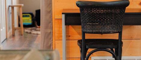 A room with a wooden wall, a black woven chair, and a wooden floor.