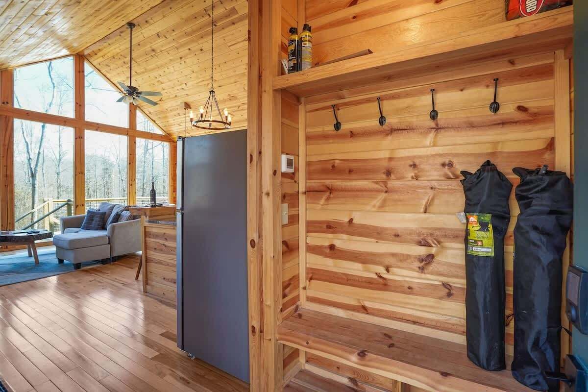 A wooden interior with a sofa, a ceiling fan, and a wall-mounted rack with items.