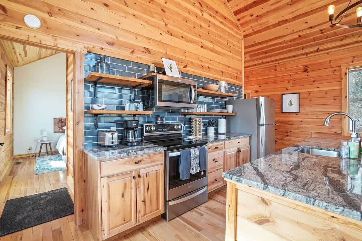 A modern kitchen with wooden cabinets, a granite countertop, and stainless steel appliances.