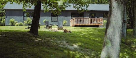 A building with a deck, surrounded by trees and grass.