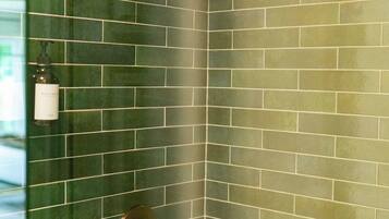 A corner of a room with green-tiled walls and a shower area.