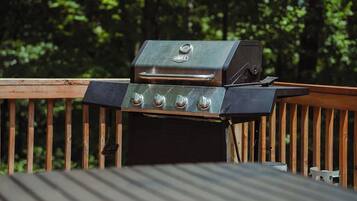 A grill on a wooden deck with a metal railing.