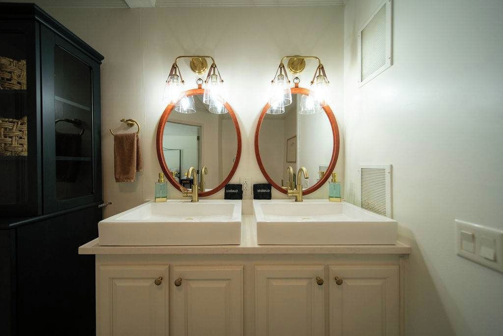 A bathroom with two sinks, a mirror, and a cabinet.