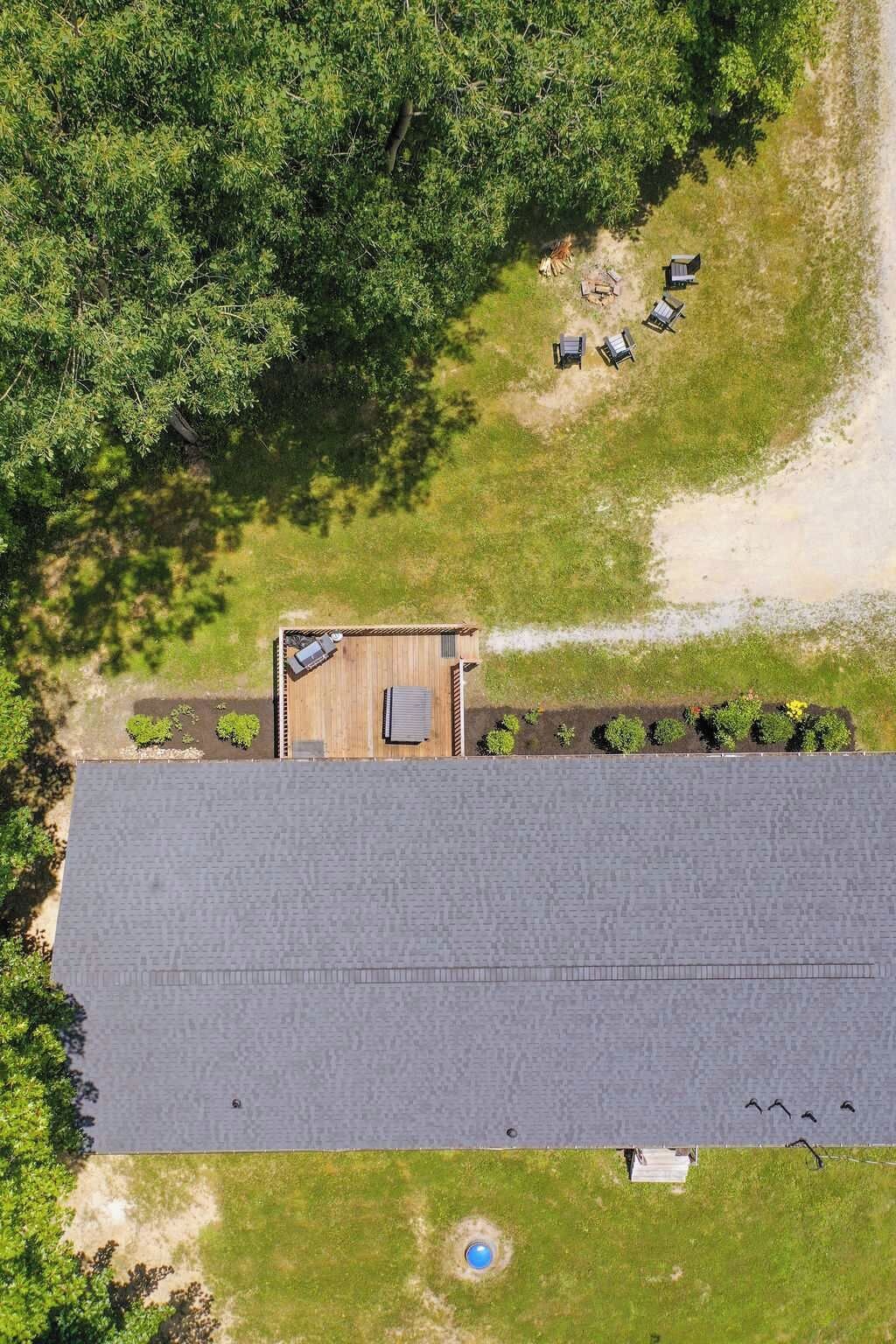 An aerial view of a property with a large building, a covered outdoor area with seating, and a swimming pool.