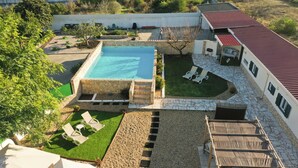 A rooftop pool with a stone deck, a grassy area with lounge chairs, and a covered seating area. - Tree House Casa Laranjeira (Sesimbra)