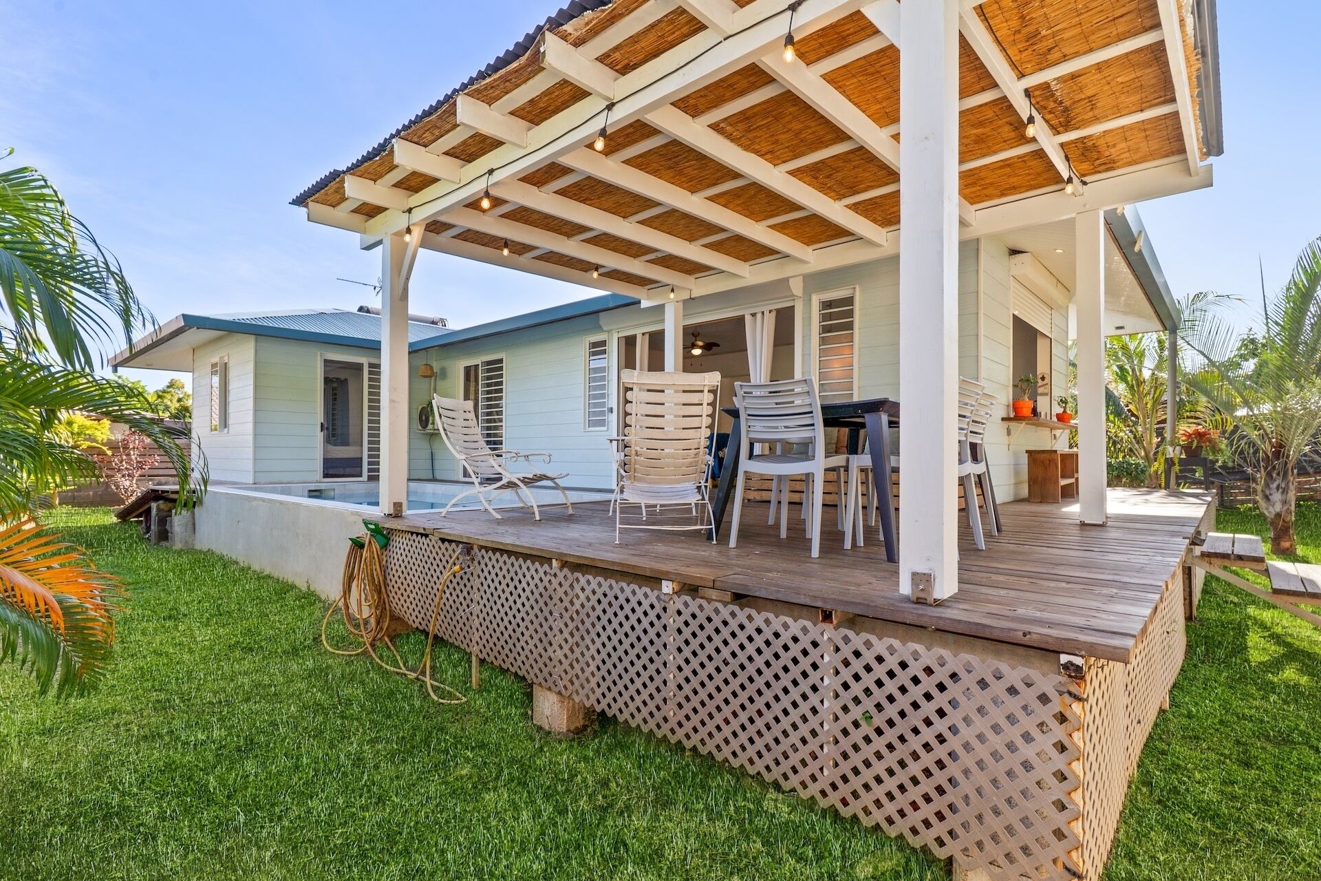 A covered outdoor area with a pool, lounge chairs, and a table.