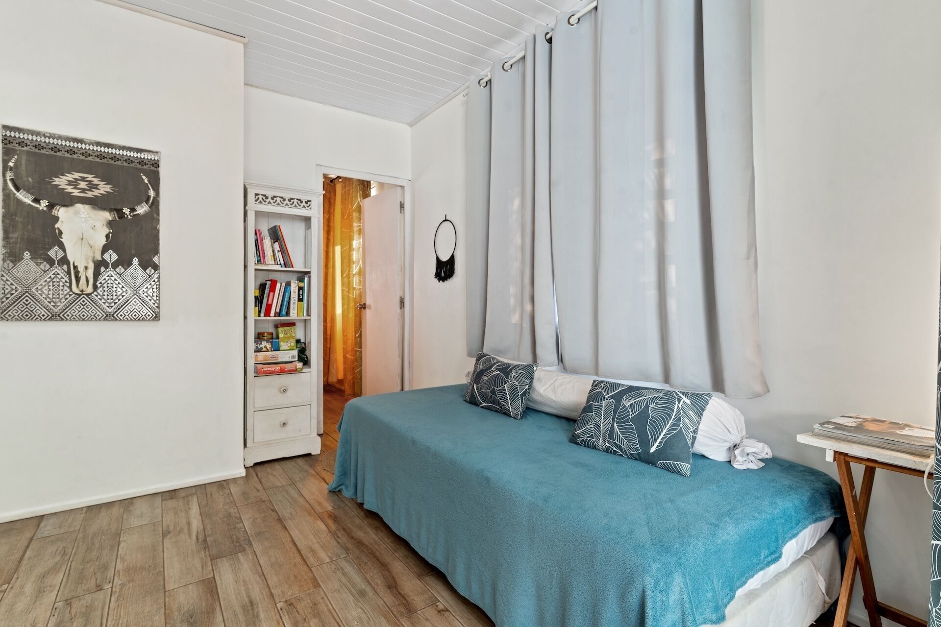 A bedroom with a bed, a bookshelf, and a door leading to another room.
