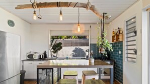 Une cuisine moderne dotée d’un îlot central, de tabourets de bar, d’un luminaire suspendu et offrant une vue sur l’extérieur.