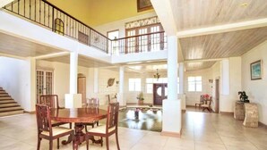 A spacious, multi-level interior with a central dining area, a staircase, and a view of a courtyard. - Landsdown House - by Zenbreak (Oistins)