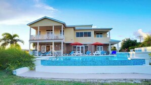 A two-story house with a swimming pool, a covered patio, and a balcony. - Landsdown House - by Zenbreak (Oistins)