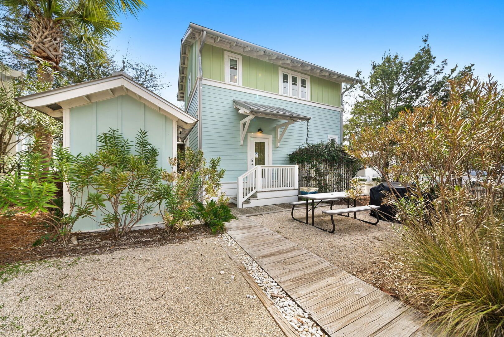 A two-story house with a porch, a small deck, and a picnic table.
