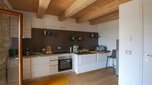 Une cuisine avec des poutres en bois, un poêle, une machine à café et un tabouret de bar.