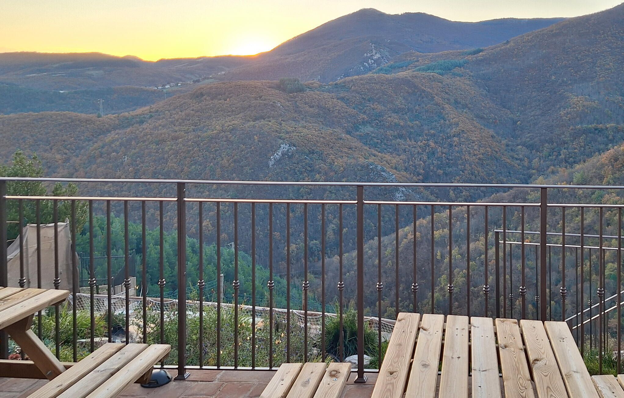 A balcony with a view of a mountainous landscape during sunset.