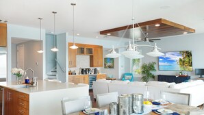 Cozinha moderna com ilha central, armários de madeira e iluminação pendente.