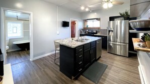 Cozinha moderna com ilha central, eletrodomésticos de aço inoxidável e ventilador de teto.