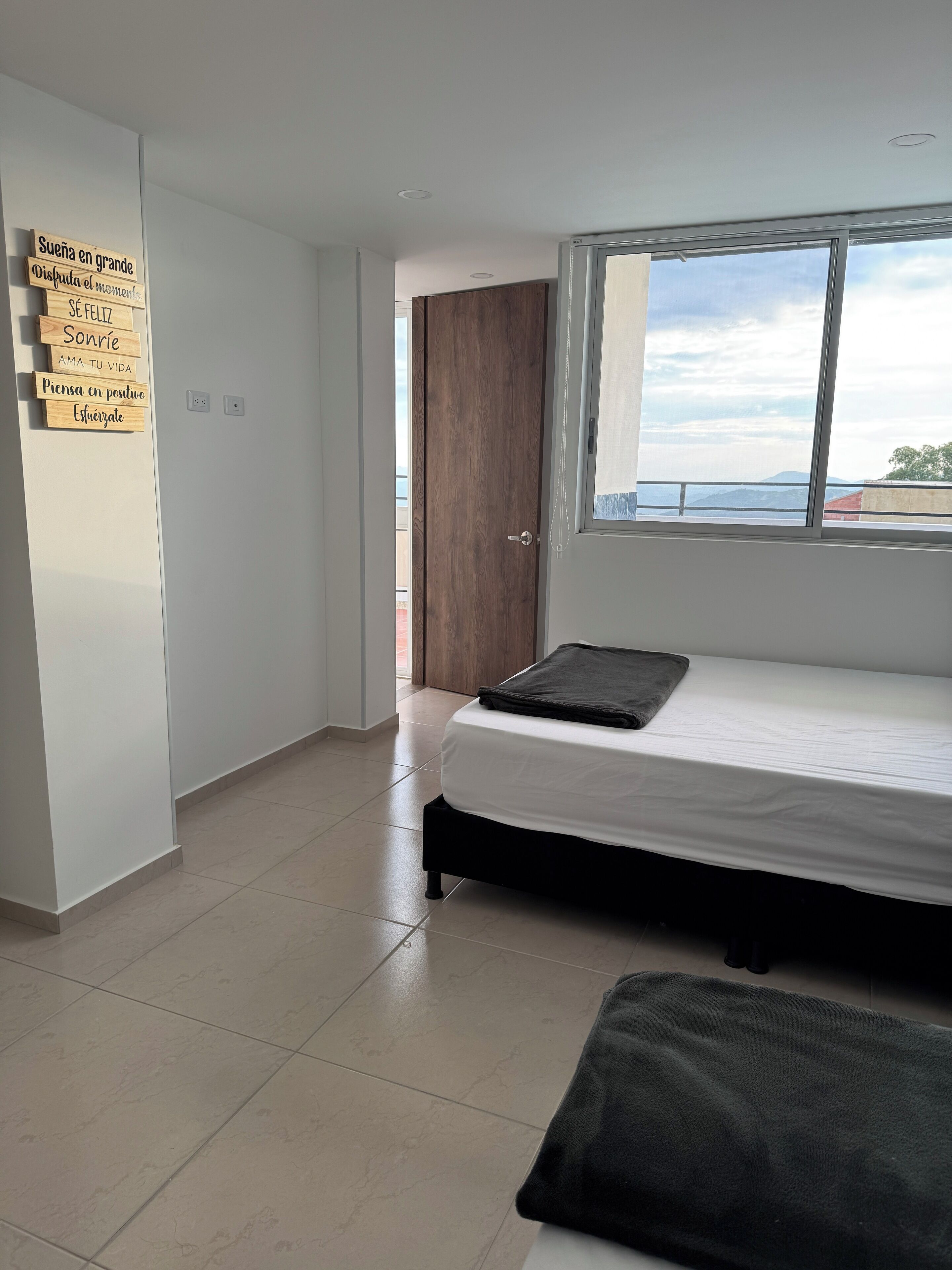 Un dormitorio con cama, ventana, armario y decoración mural motivacional.