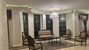 A spacious room with a chandelier, large windows, and classic furniture.