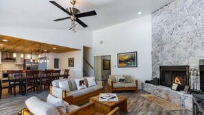 A spacious living room with a fireplace, wooden furniture, and a stone accent wall.