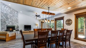 A dining area with a wooden table and chairs, a stone wall, a fireplace, and a large window.