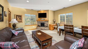 A living room with a fireplace, leather sofas, a dining table, and chairs.