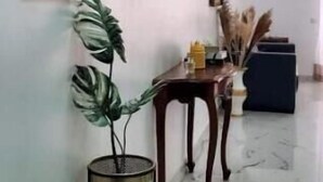 A hallway with a marble floor, a wooden table with a vase of dried flowers, and a framed picture on the wall. - Lovely space to relax (Santo Domingo)