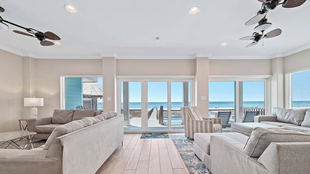 A spacious living area with a view of the ocean, a ceiling fan, and a large window.