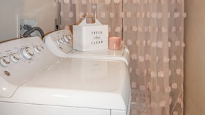 Un espace buanderie comprenant un lave-linge, un sèche-linge et un étendoir à linge.