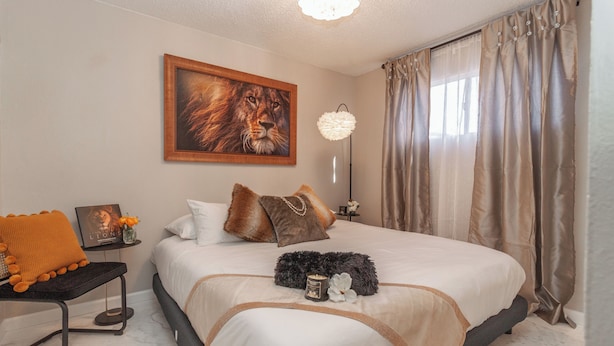 Un lit bien fait, avec une couette blanche et un plaid décoratif.