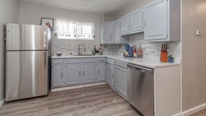 Une cuisine moderne avec des meubles gris, un réfrigérateur en acier inoxydable et un lave-vaisselle.