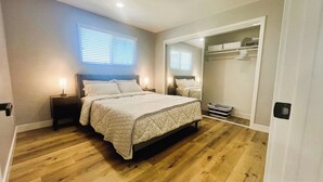 Un dormitorio con cama, mesitas de noche, un espejo y un vestidor.