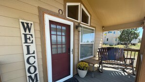 A wooden deck with a welcome sign, a red door, a potted plant, and a wooden chair. - Cozy Cabin w/ loft in charming Colorado Springs near USAFA (Colorado Springs)