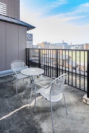 A balcony with two metal tables and chairs, a view of the cityscape, and a building with a grey facade. - Hotel Elite Kyoto Station (Kyoto)