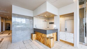 A modern hotel reception area with a marble counter, a herringbone wood accent, and a glass door leading to the elevator. - Hotel Elite Kyoto Station (Kyoto)