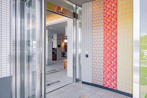 A modern hotel entrance with a glass door, a tiled floor, and a wall with patterned wallpaper. - Hotel Elite Kyoto Station (Kyoto)