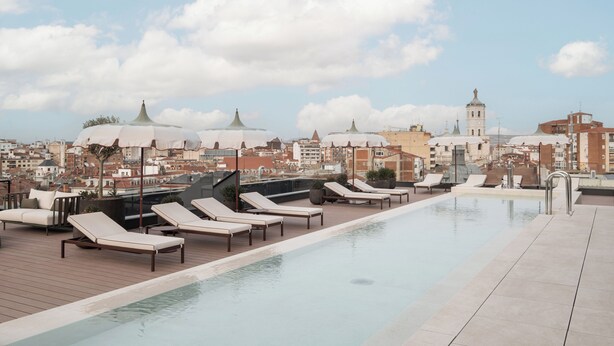A rooftop pool with lounge chairs, a cityscape view, and a bell tower in the background. - Eurostars Valladolid (Valladolid)